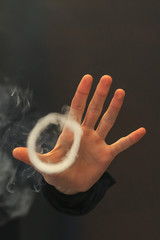 A ring of vapor from an electronic cigarette and hand for background. Vaping.