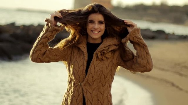 Gorgeous female model moving long silky hair in front of the ocean at sunset slow motion
