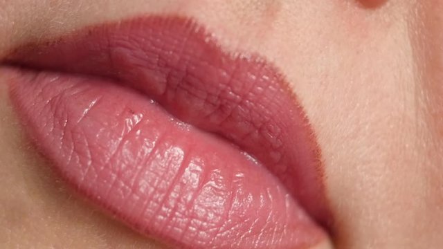 Close up of a beautiful toothy female smile with soft red lipstick on her lips and clean white teeth