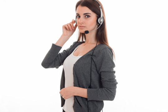 young pretty brunette business woman with headphones and microphone looking at the camera isolated on white background