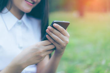 Beautiful Young asian woman smiling while reading her smartphone