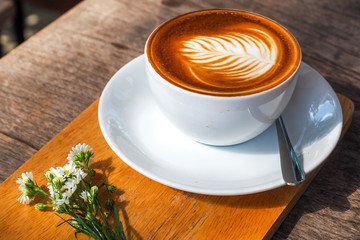Coffee cup on a wooden table and a Little flower.