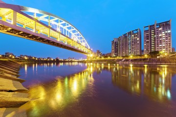 Riverside buildings and the famous HuanDong Rainbow Bridge over Keelung River at dusk in Taipei Taiwan, Asia ~ A romantic landmark of Taipei, the Rainbow Bridge in evening twilight ( low angle view )