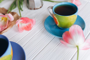 Pink tulips and coffee cups. Mother`s Day or Women`s Day on a white background 