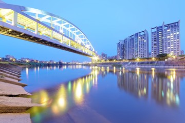 Riverside buildings and the famous HuanDong Rainbow Bridge over Keelung River at dusk in Taipei Taiwan, Asia ~ A romantic landmark of Taipei, the Rainbow Bridge in evening twilight ( low angle view )