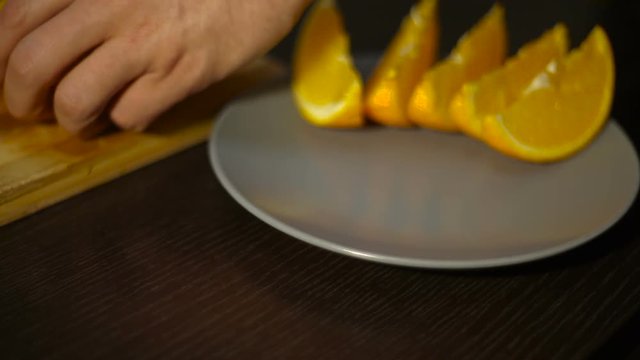 man puts the cut orange on a plate