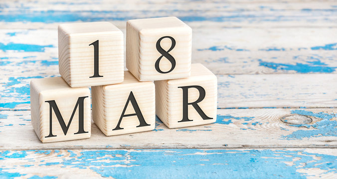 March 18th. Wooden cubes with date of 18 March on old blue wooden background.