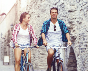 Obraz premium Young couple of hipsters riding a bicycle. Date in old town. Love, relationship, romance concept.