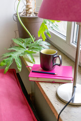 still life / Pink notebook, pen and cup on the window sill 