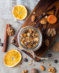Fototapeta na wymiar Homemade granola with nuts and dried oranges in jar with copy space, top view
