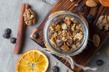 Homemade granola with nuts and dried oranges in jar, top view