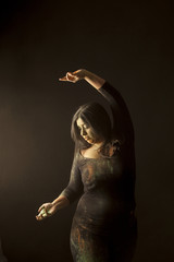 Young indian woman isolated dancing and playing with colored dust in dark clothes