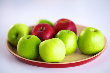 Still life arrangement of apples on a wooden platter
