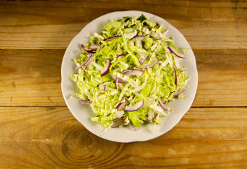 Salad with chinese cabbage and onion on wooden table