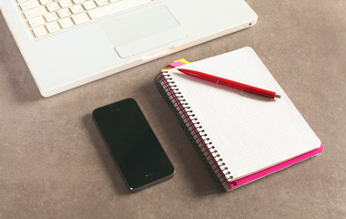 surface of a table with notebook, smartphone, eye glasses, and pen
