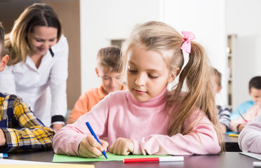 Teacher and elementary age children drawing at classroom