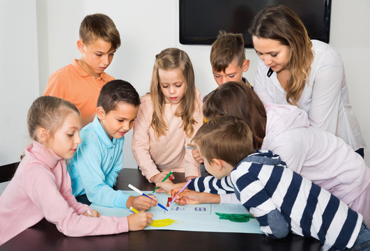 Children with teacher drawing together in classroom