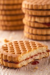 Several biscuits with red homemade marmalade on light wooden board