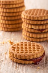 Several biscuits with red homemade marmalade on white wooden board
