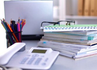 A note book, laptop, pen, graph paper document on the office desk table behind white blind