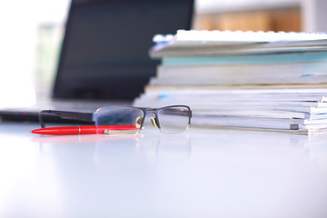 A note book, laptop, pen, graph paper document on the office desk table behind white blind