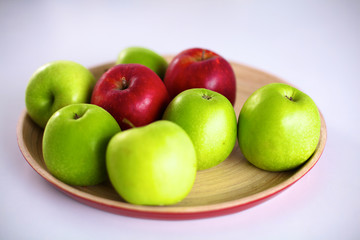 Still life arrangement of apples on a wooden platter
