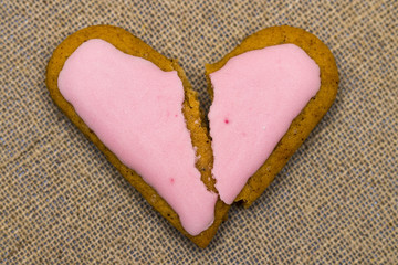 Naklejka na ściany i meble Cracked heart shaped cookie decorated with red icing as a concept of broken heart