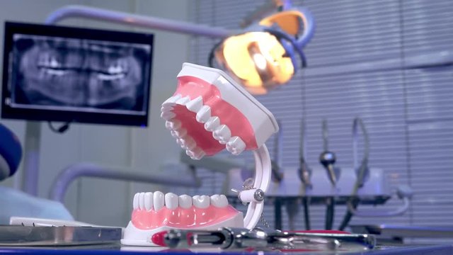 Tooth model instruments on the dentist table and panoramic x-ray image in the background