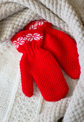 Winter baby clothes, scarf and mittens on wooden background