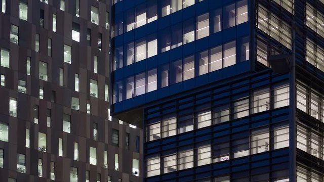 Office building, with illuminated interior at dusk, in the city of Barcelona.Motion Camera zoom out.