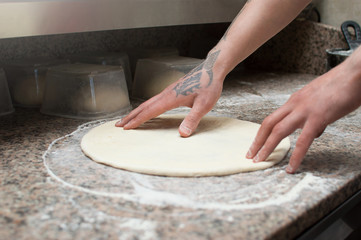 Close-up of male hands baker kneads raw pizza dough. Fast food. Pizza delivery.