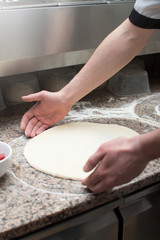 Fototapeta premium Close-up of male hands baker kneads raw pizza dough. Fast food. Pizza delivery.