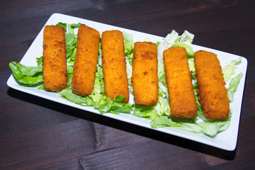 Fish sticks on tray on a wooden table seen from above