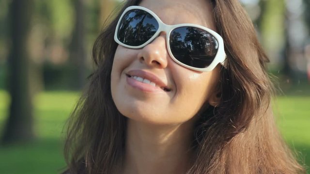Happy young woman in sunglasses at the summer park