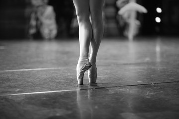 Elegant legs of a ballerina standing on pointe on stage during a performance