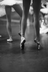 Elegant legs of a ballerina standing on pointe on stage during rehearsal