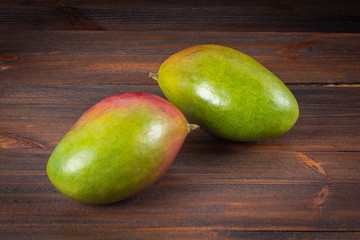 Tropical fruit mango on a wooden background, whole or sliced.