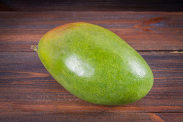 Tropical fruit mango on a wooden background, whole or sliced.