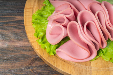 Sliced sausages with salad leaves on the wood background © detry26