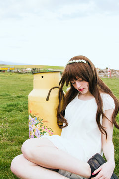 Preciosa chica de cabello castaño con una lechera de metal decorada con flores 