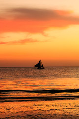 Obraz na płótnie Canvas Traditional sailing boat and a tropical sunset on a calm ocean