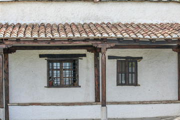 Fachada con tejado de tejas y ventanas de hierro, madera y cristal en cortijo