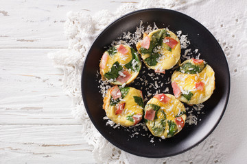 Tasty breakfast: frittata with spinach, ham and cheese close-up. Horizontal view from above