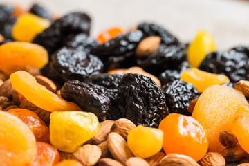 prunes, dried apricots, dried mandarins and almonds on a light wooden background