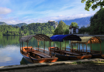 Traditional wooden boats on the lake Bled against famous old castle on the cliff, Slovenia