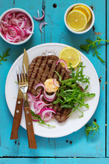 Roasted beef steak with onions and herbs.