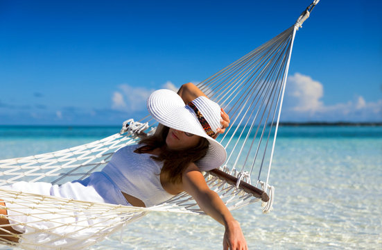 Attraktive Frau mit weißem Hut entspannt auf einer Hängematte in den Tropen