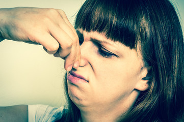 Woman holding her nose - bad smell concept