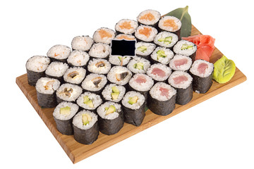 Assorted small rolls on a wooden Board with sheets of leek, wasabi, ginger