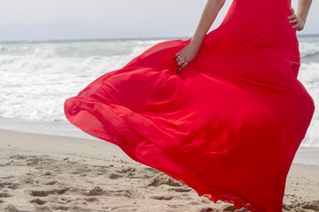 Beautiful red dress flowing in the wind at the beach. Cropped.